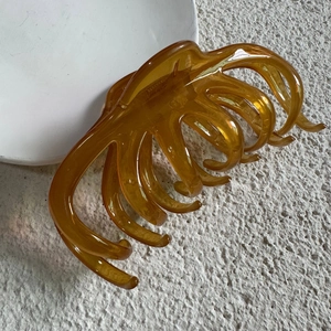 Top view of a large amber jelly octopus hair claw clip on a white textured background