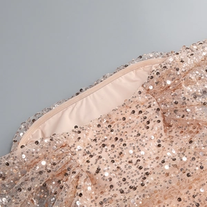 Close-up of champagne gold sequins and fabric texture on off-shoulder dress detail
