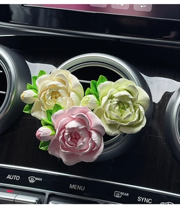 Macro shot of pink and white ceramic jasmine flower clips on a car air vent