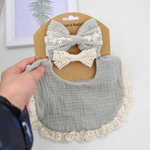 Detail of grey muslin cotton bib with lace trim and matching bow headbands set