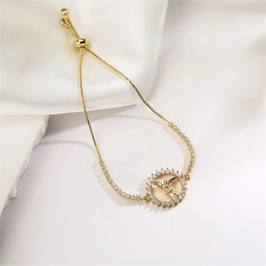 Detail of adjustable gold bracelet featuring a round angel charm with cubic zirconia