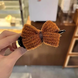 Close-up of brown knitted bow hair claw clip showing texture and secure black fastener