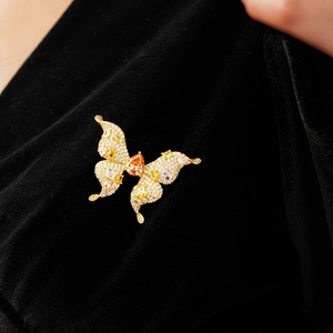 Macro detail of gold butterfly brooch with yellow zircons and pear-shaped amber stone
