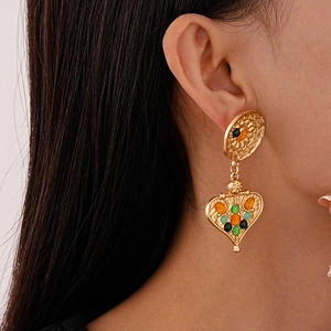 Macro detail of vintage gold heart earrings with colorful stones on female model