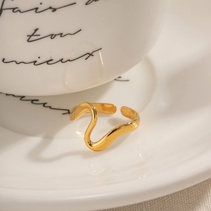 Elegant gold wavy snake ring with irregular curved design on a minimalist white tray