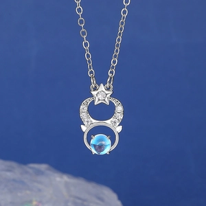Close-up of star and crescent moon pendant with blue moonstone and sparkling crystals