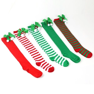 Detail of Christmas over-knee socks with bows and pom-poms in striped festive patterns