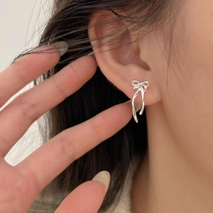Close-up of minimalist silver bow stud earrings worn by a model for a stylish look