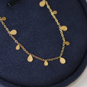 Gold-plated teardrop pendant necklace for women shown on a blue velvet display