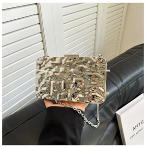 Macro view of metallic silver evening clutch with hammered ripple texture and chain strap