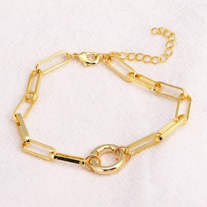 Gold plated paperclip link bracelet featuring a large spring ring clasp on beige linen