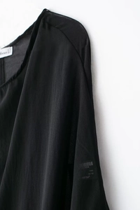 Détail de l'épaule et de la manche d'une robe en mousseline noire avec étiquette de taille