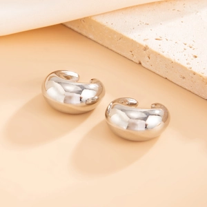 Detailed view of silver thick chunky C-shaped hoop earrings on a textured stone base