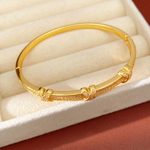 Detailed close-up of 18k gold plated X-shaped bangle with pavé-set cubic zirconia accents