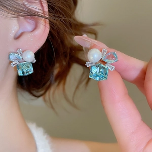 Detailed view of silver stud earrings with blue square crystal and pearl butterfly design