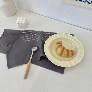 French cream ceramic dinner plate with ruffled edge and wooden handle metal spoon
