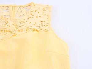 Detail shot of elegant yellow sleeveless top with intricate floral lace neckline and cotton texture