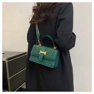 Vue détaillée du sac en cuir tressé vert foncé avec boucle H dorée sur fond blanc pur