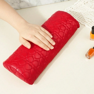 Detail of red heart-quilted PU leather nail arm rest with a hand resting on marble