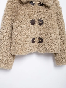 Detailed view of camel fleece jacket featuring dark brown leather patches and gold buckles