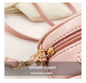 Detail shot of smooth gold-tone metal zipper on a pink faux leather bag