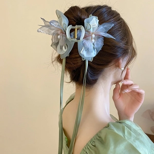 Close-up of elegant light green fabric butterfly hair clip with pearls on model back hair