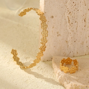Gros plan sur une bague fleurie mate plaquée or 18 carats et un jonc sur pierre
