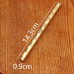 Detailed close-up of a vintage bamboo-shaped brass pen on a textured wooden surface