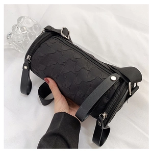 Detail of black cylindrical crossbody bag with pleated texture and silver zipper finish