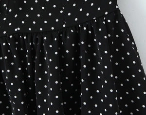 Détail de la robe noire à pois avec plis délicats et texture de tissu de haute qualité
