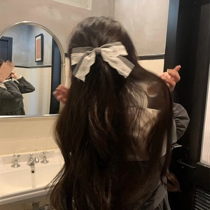 Detail of grey lace bow hairpin with ribbons on hair in a retro bathroom setting