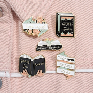 Detailed close-up of five colorful enamel book badges pinned on pink denim fabric