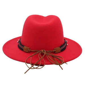 Detail of red wool felt fedora with black studded band and brown leather bow accent