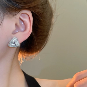 Detail of silver geometric triangle stud earrings with zircons worn by a model
