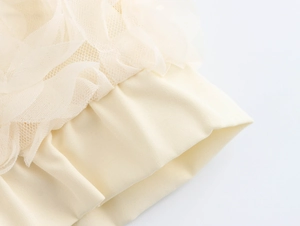 Close-up of elegant cream-colored knit fabric with delicate mesh lace embroidery details
