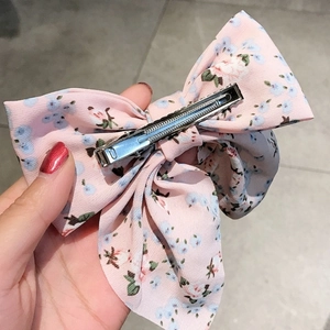 Detailed view of the silver metal duckbill clip and pink floral fabric of the bow hair clip