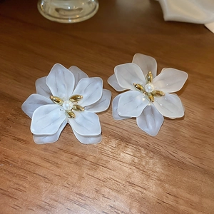Detail shot of white matte flower earrings with golden stamens and pearl centers