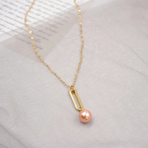 Minimalist gold lip chain necklace with pink pearl pendant on a soft grey textured fabric