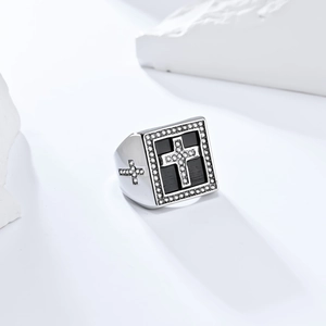 Close-up of hip hop square ring with iced out cross design on black enamel background