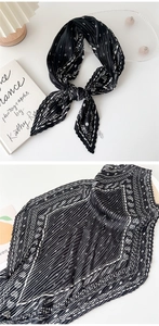 Detailed view of black pleated silk scarf with elegant prints and accordion texture