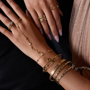 Close-up of luxury 18k gold heart bracelet and crystal rings on model with black background