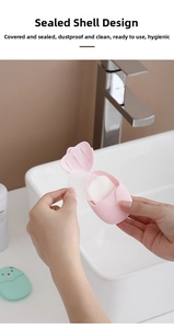 Hand taking soap paper from pink bear-shaped portable box near a bathroom faucet