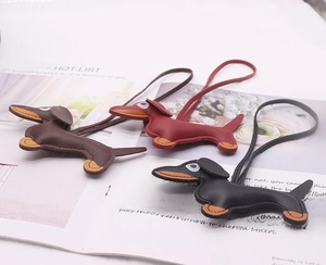Detailed view of leather dachshund bag charms in brown, burgundy, and black finishes