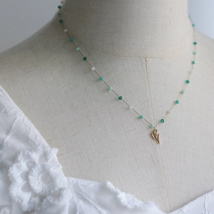 Detail of 18K gold tulip necklace with vintage green and white faceted beads on model