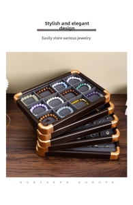 Detail of stacked walnut jewelry trays with grey velvet slots and golden metal corners