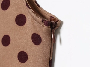 Close-up of invisible zipper and polka dot fabric detail on a retro midi dress