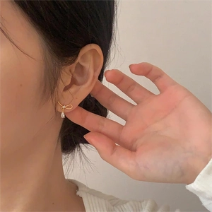 Elegant gold bow earrings with crystal water drop pendants worn by a model