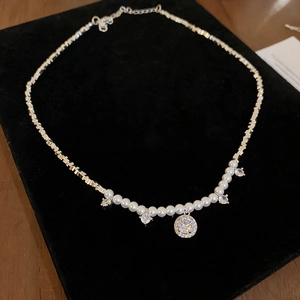 Détail du collier de perles élégant avec chaîne argentée et pendentifs en zircon brillants