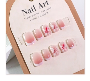 Close-up of pink ombre press-on nails with 3D floral accents and French tips