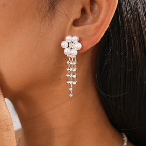 Close-up of elegant flower earrings with white pearls and sparkling rhinestone tassels